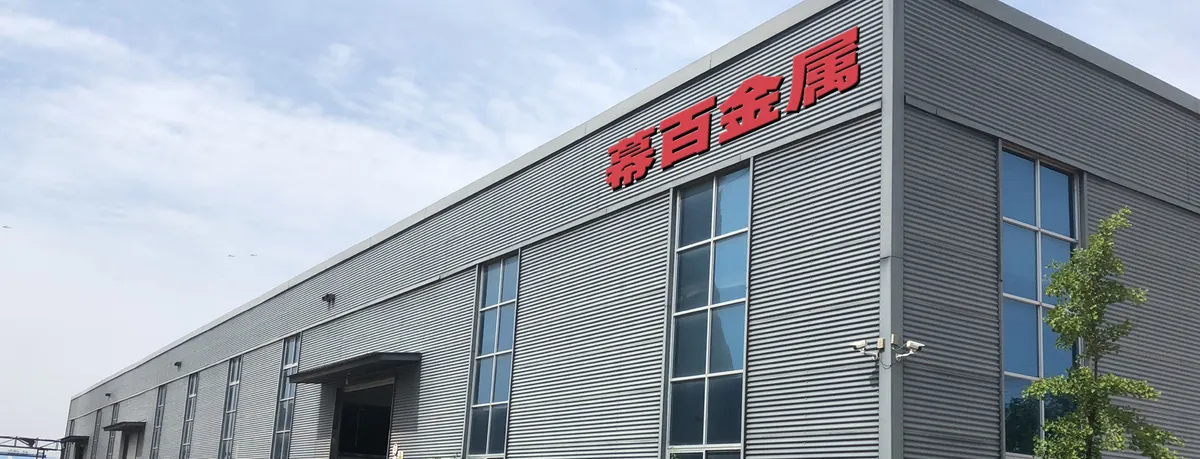 幕百金属无锡厂区外景，厂房屋面挂着红色「幕百金属」厂牌